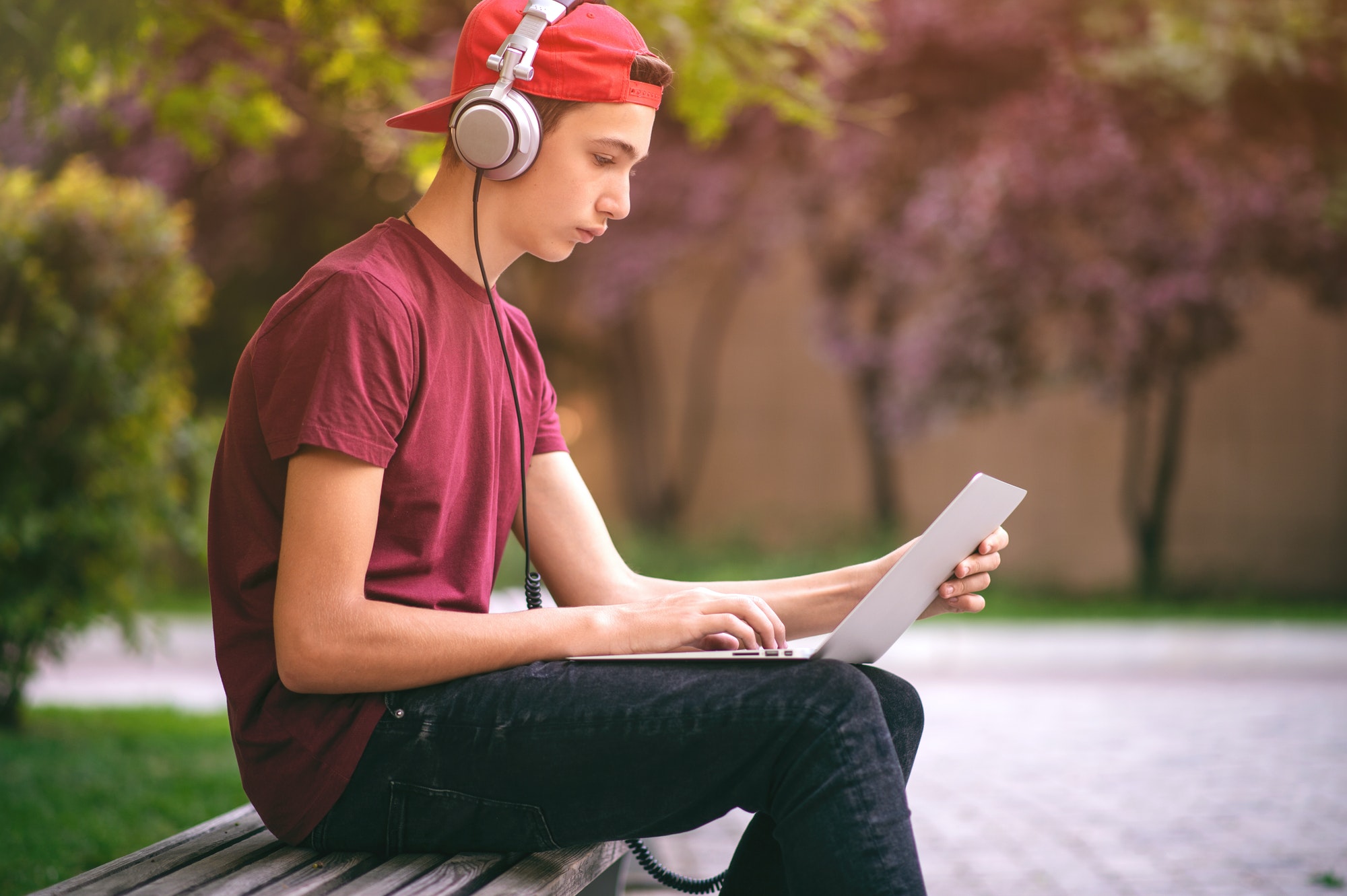 Teenage boy with a laptop in the park.